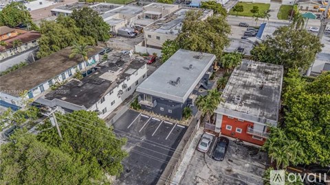 A parking lot is surrounded by buildings and trees.