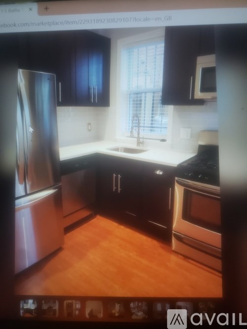 A kitchen with a stainless steel refrigerator, black cabinets, and a wooden floor.
