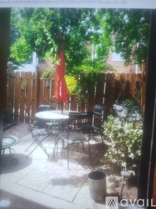 A patio with a table and chairs and a red umbrella.