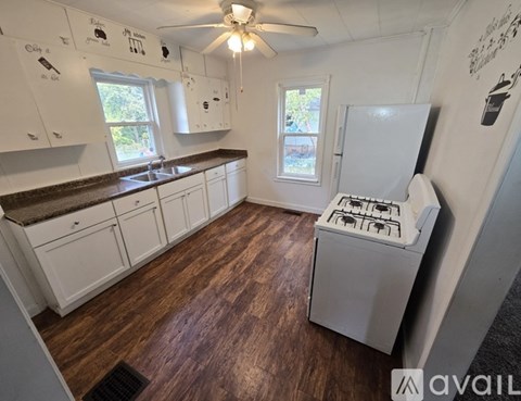 A kitchen with white cabinets and a white stove top oven.
