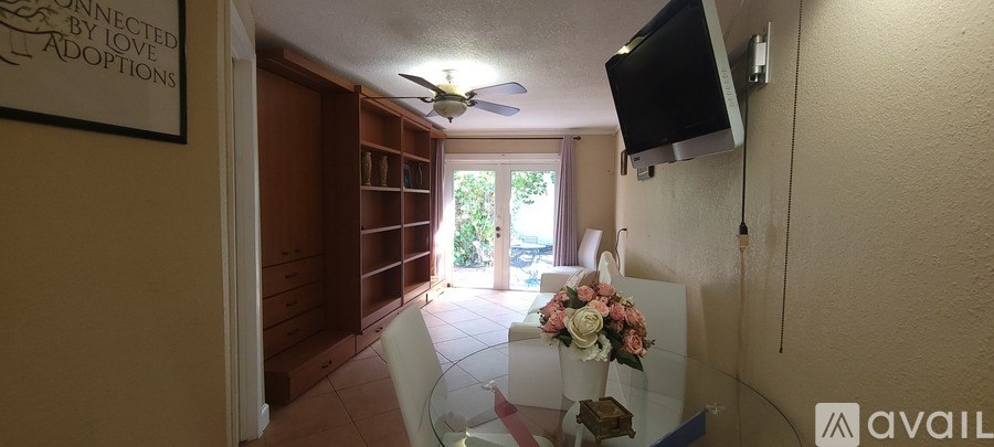 A room with a ceiling fan and a flat screen TV mounted on the wall.