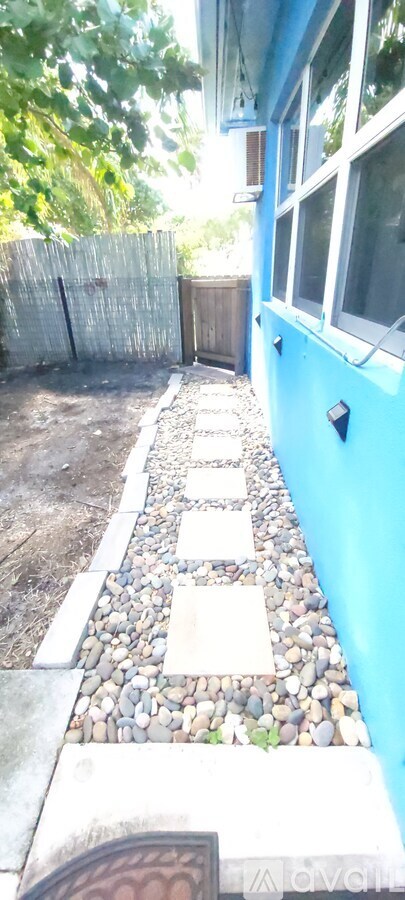 A blue building with a white window and a wooden fence.
