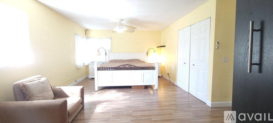 A bedroom with a bed, a chair, and a ceiling fan.