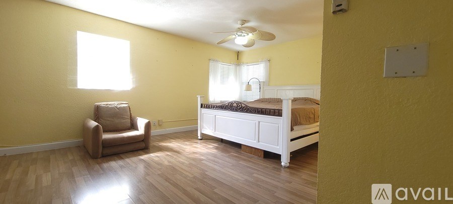A bedroom with a bed, chair, and window.