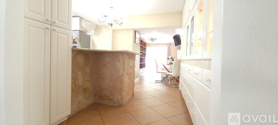 A hallway with a white wall and a brown floor.