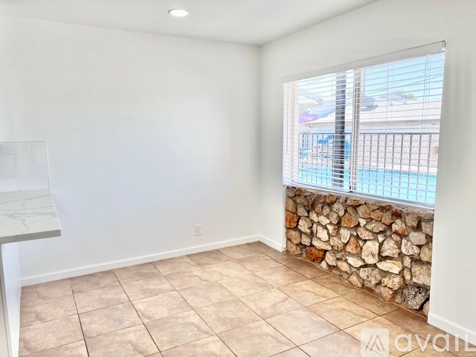 A room with a stone wall and a window overlooking a pool.