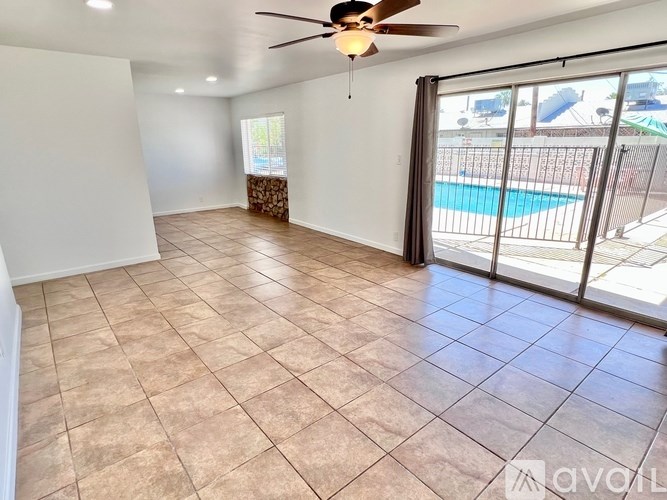 A room with a ceiling fan and sliding glass doors leading to a pool.