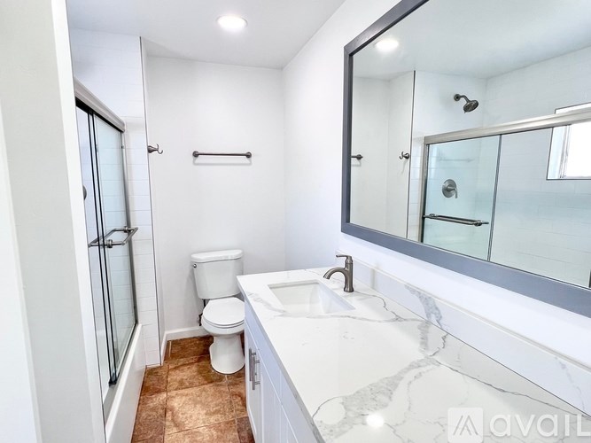 A white bathroom with a toilet, sink, and mirror.