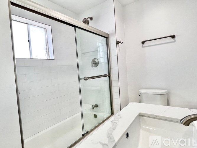 A white bathroom with a glass shower door and a toilet.