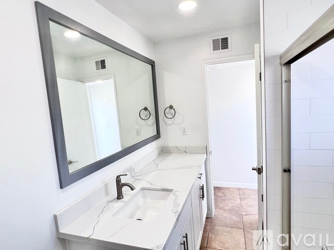 A bathroom with a sink, mirror, and two clocks on the wall.