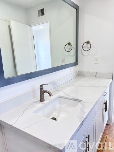 A white sink with a silver faucet and a mirror above it.