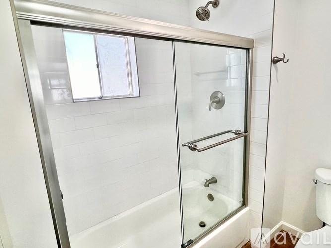 A white bathroom with a glass shower door and a toilet.