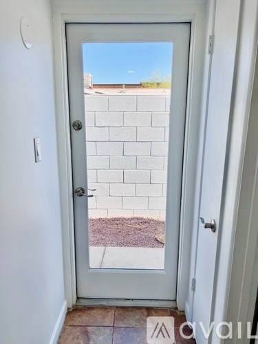 A door with a glass window leading to a brick wall.