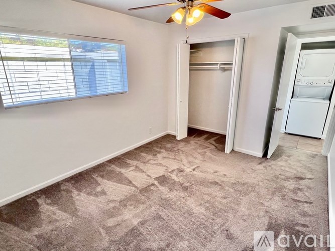 A room with a ceiling fan and a window with blinds.