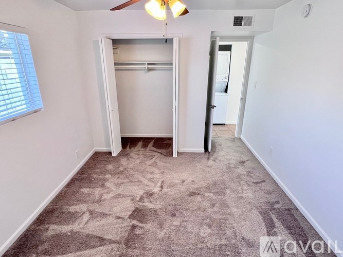 A room with a carpeted floor and a ceiling fan.