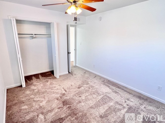 A room with a carpeted floor and a ceiling fan.