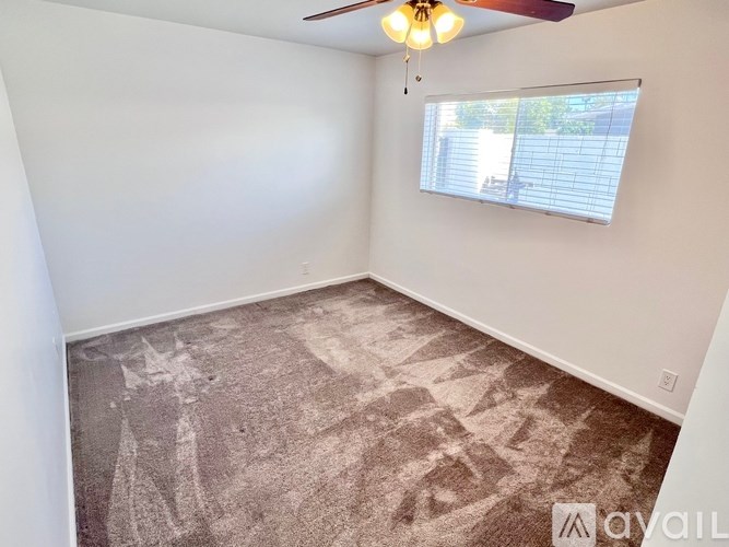 A room with a ceiling fan and a window with blinds.