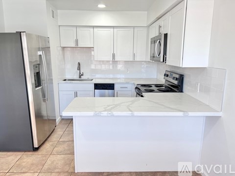 A kitchen with white cabinets and a marble countertop.