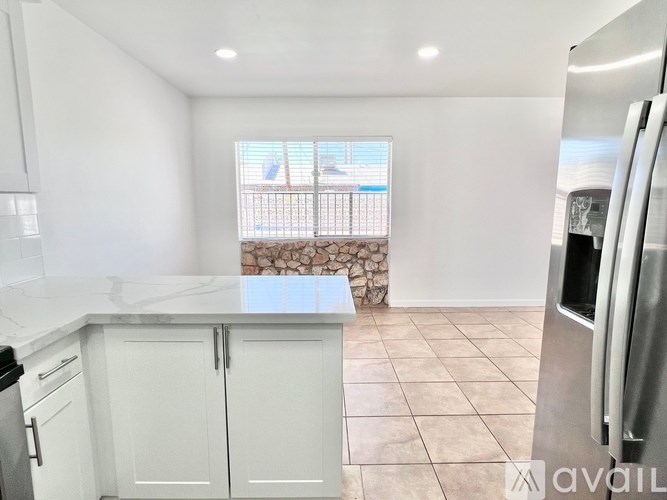 A kitchen with white cabinets and a marble countertop.