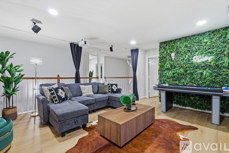 A living room with a grey couch, a wooden coffee table, and a green plant wall.
