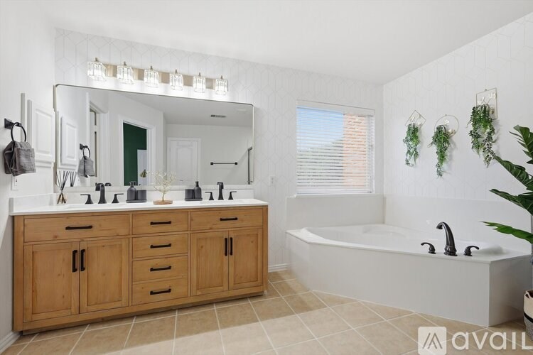 A bathroom with a large mirror, double sinks, and a bathtub.