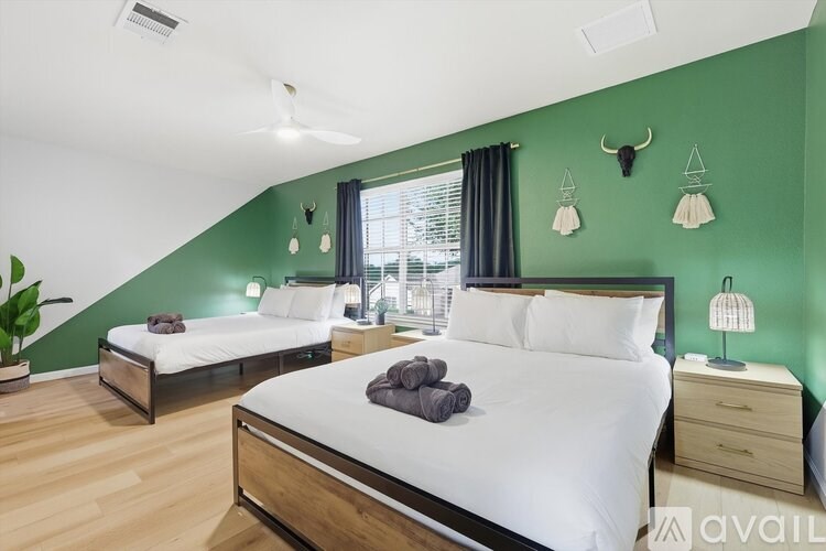 A bedroom with two beds and a green wall.