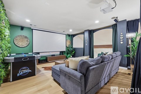A living room with a grey couch and a pool table.