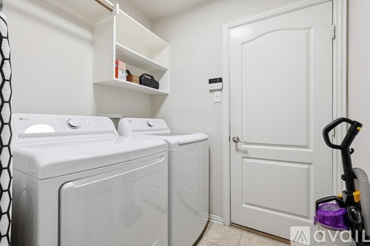 A laundry room with a washer and dryer and a vacuum cleaner.