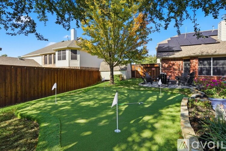 A backyard with a putting green and a flag.