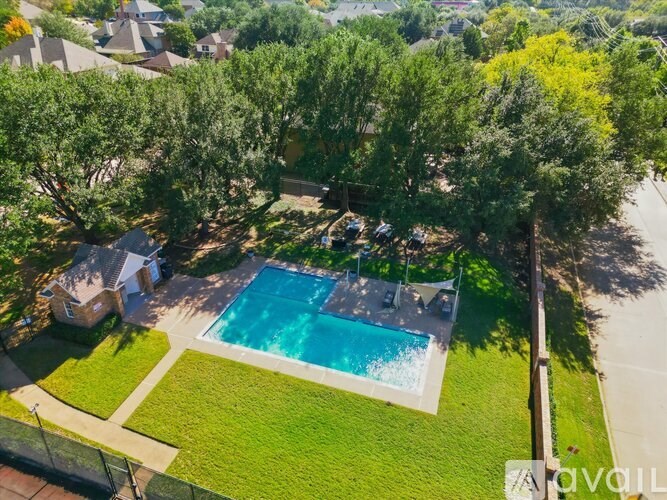 A bird's eye view of a house with a swimming pool surrounded by trees.