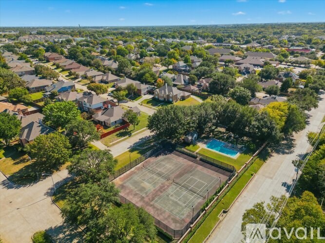 A tennis court is surrounded by houses in a residential area.