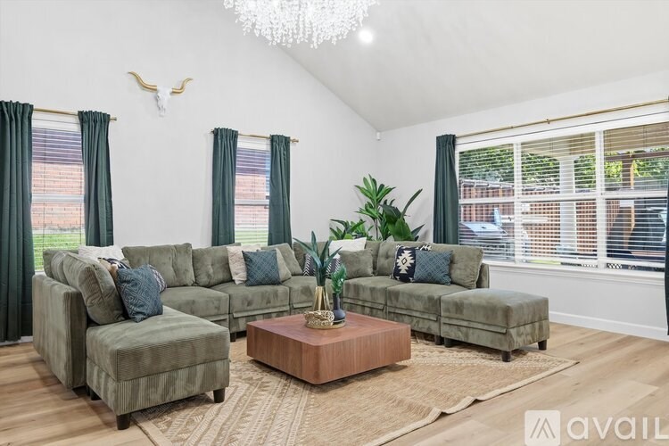 A living room with a large sectional sofa, a coffee table, and a chandelier.