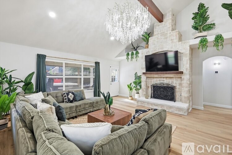 A living room with a fireplace and a television mounted above it.