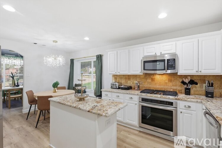 A kitchen with white cabinets and granite countertops.