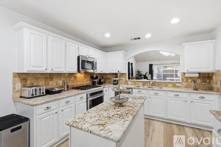 A kitchen with white cabinets and granite countertops.