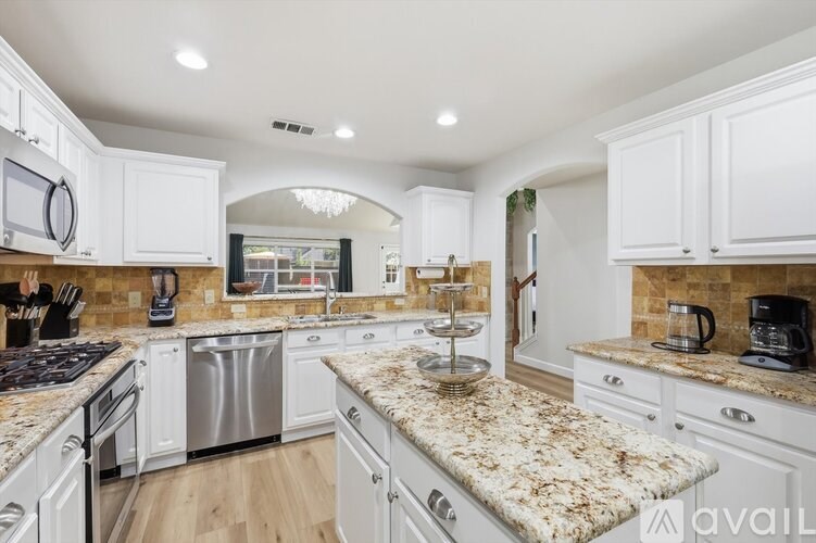 A kitchen with white cabinets and granite countertops.