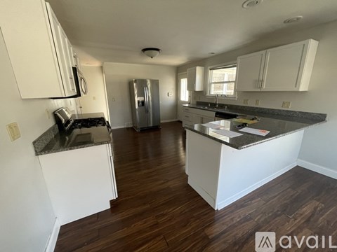 A kitchen with white cabinets and a granite countertop.