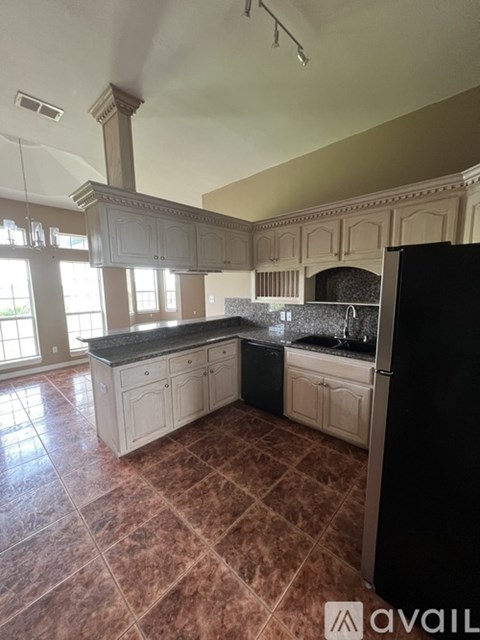 A kitchen with a black refrigerator and a marble countertop.