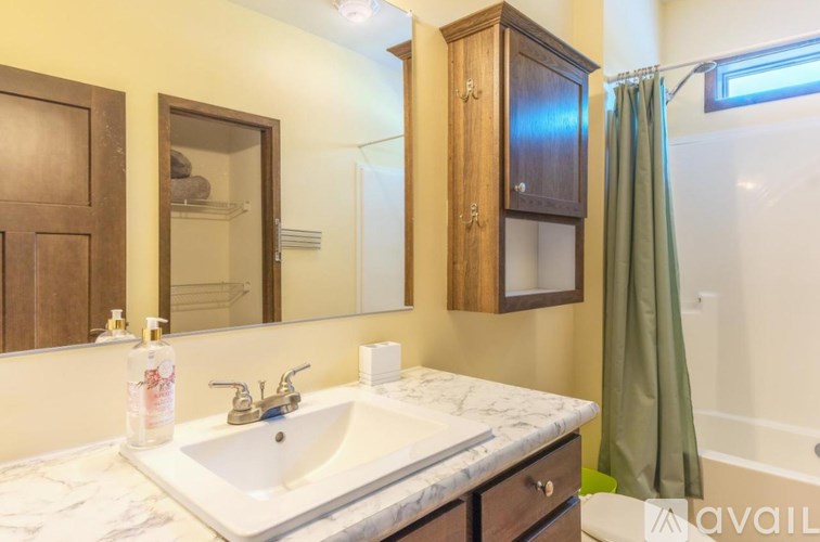 A bathroom with a marble countertop and a green shower curtain.