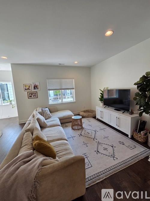 A large open plan living and kitchen area with wooden floors and a staircase on the left.
