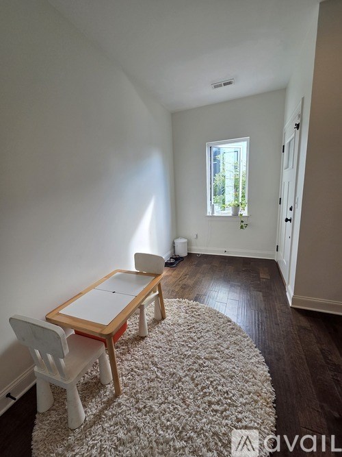 A white chair sits in front of a table in a room with a window.