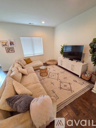 A living room with a large sectional sofa and a flat screen TV mounted on the wall.