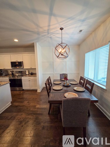 A dining room with a table set for four and a kitchen in the background.