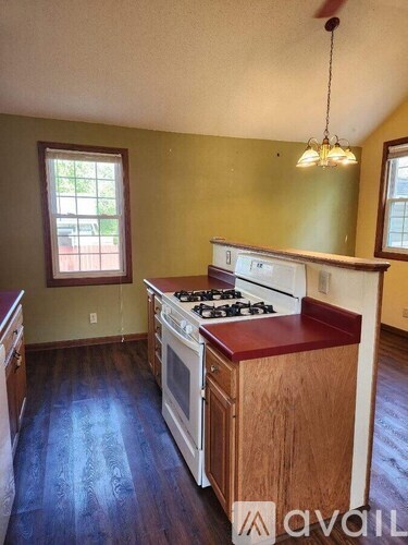 A kitchen with a stove top oven and wooden cabinets.