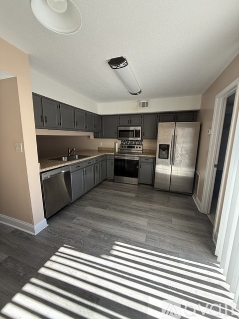 A kitchen with a refrigerator, oven, and microwave.