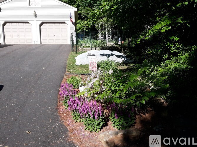 A white house with a garage and a garden in front.