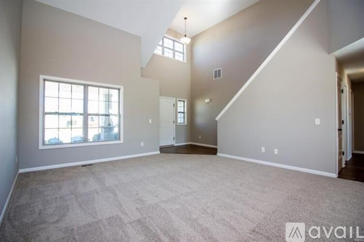A spacious room with a carpeted floor and a staircase leading to another level.