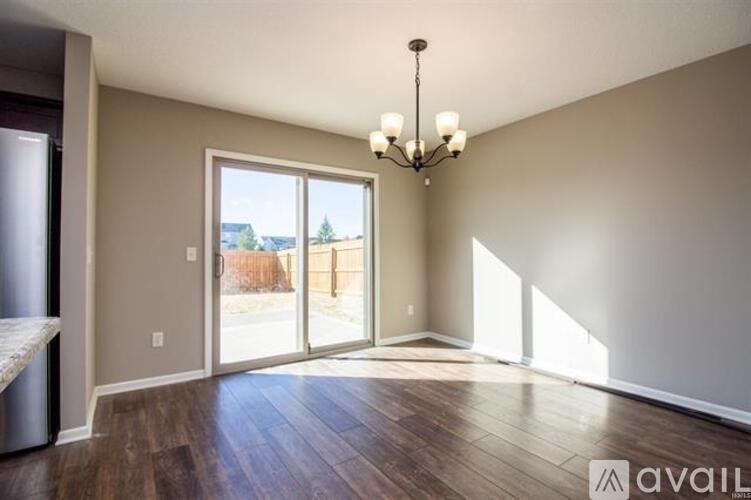 A room with a chandelier, sliding glass doors, and hardwood floors.