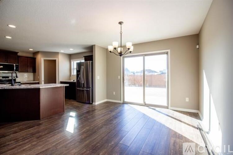 A well-lit kitchen with dark wood floors and a chandelier.