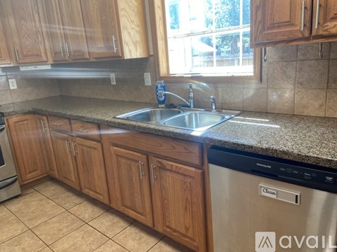 A kitchen with wooden cabinets and a stainless steel dishwasher.